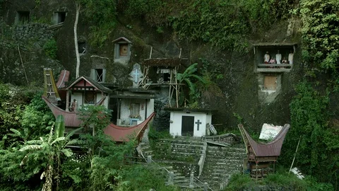 Typical Toraja tombs in a vertical rock face carved with traditional puppets Stock Footage 102592437