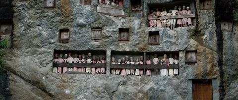 Typical Toraja tombs in a vertical rock face carved with traditional puppets Stock Footage 102596310