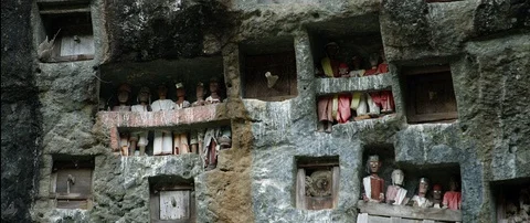 Typical Toraja tombs in a vertical rock face carved with traditional puppets Stock Footage 102599299