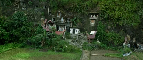 Typical Toraja tombs in a vertical rock face carved with traditional puppets Stock Footage 102652451