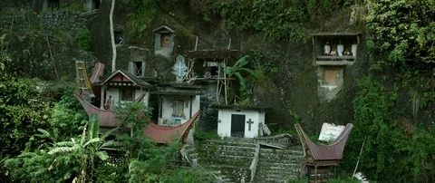 Typical Toraja tombs in a vertical rock face carved with traditional puppets Stock Footage 102654726