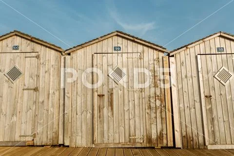 Typical wooden beach huts at seaside in Normandy, France on bright sunny day Stock Photos