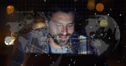 Typing bearded developer wearing plaid shirt, leaning over laptop at home, Foto stock