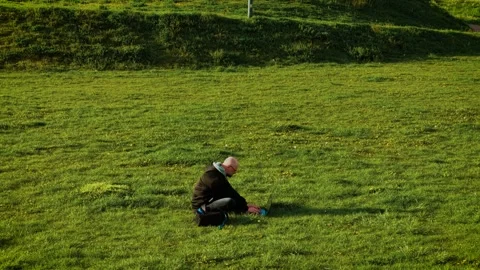 Typing communicating in working chat online while sitting on grass. Freelancer Stock Footage 318236531
