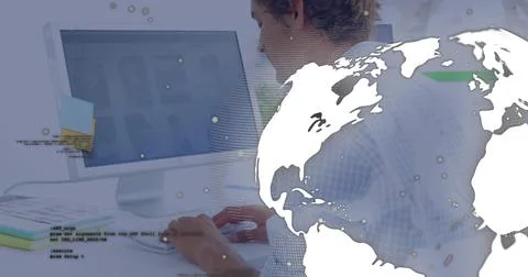 Typing curly-haired male programmer using keyboard at office desk with globe  写真素材