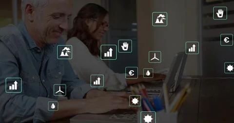 Typing denim-shirted senior using keyboard at wooden table with laptops and data Stock Photos
