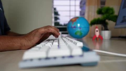Typing at Desk with Globe and Rocket Model, Person typing on a keyboard wit.. Stock Footage 316799977