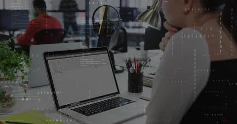 Typing developer examining code on laptop at open-plan office, with lamp and 스톡 사진