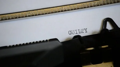 Typing the expression GUILTY with an old manual typewriter Stock Footage 73359912