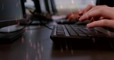 Typing hands tapping slim black keyboard at desk, with monitors, cables, binary 库存照片