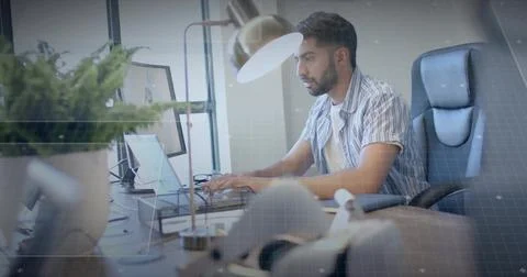 Typing Indian man using laptop at modern office workspace, with monitor and Stockfoto's