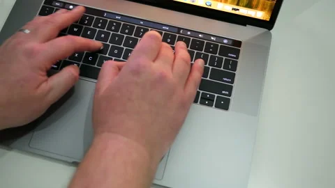 Typing on keyboard of an Apple MacBook Pro laptop on white desk. Stock Footage 237751091