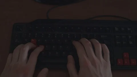 Typing on a keyboard with black and red keys. Generic wood desk, top angle shot. Stock Footage 88708898
