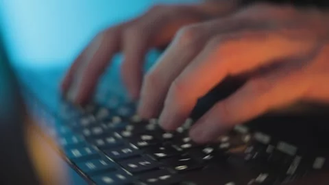 Typing on a laptop keyboard Coding or hacking in blue and orange lighting Stock Footage 332445291