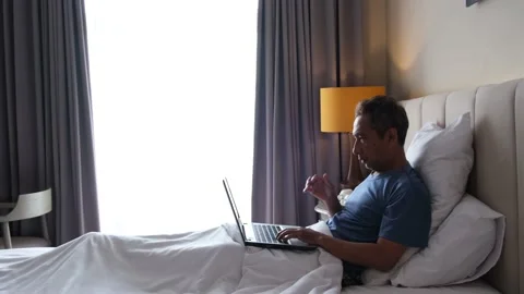 Typing on laptop, make mistake, looks disappointed holding head on bed Video stock 230742549