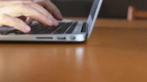 Typing on a laptop notebook keyboard while working on a table by male hands Stock Footage 129506886