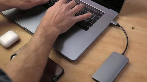 Typing on a laptop with usb-c hub connected and a mobile phone in front on wo Stock Footage 120915440
