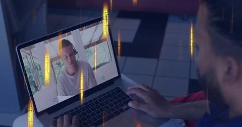 Typing local man operating laptop on lap at home, showing headset-wearing man in Stock Photos