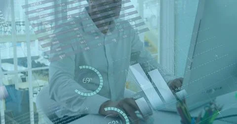 Typing middle-aged man in light shirt reviewing data at open-plan office, with Stock Photos