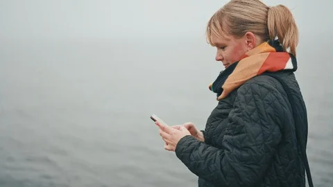 Typing on mobile phone while standing outside in cold weather Stock Footage 122259849