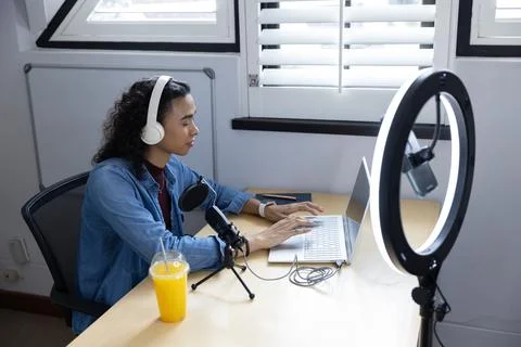 Typing non-binary creator in denim at home desk with laptop and recording gear, 写真素材