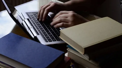 Typing on a pc / tablet with books around Stock Footage 124279125