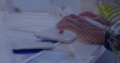 Typing right hand on white keyboard at desk, smartphone on blue charts, watch Stock Photos