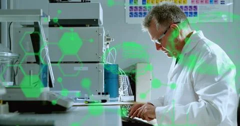 Typing scientist in lab coat and goggles at bench with keyboard, stacked modu Stock Photos