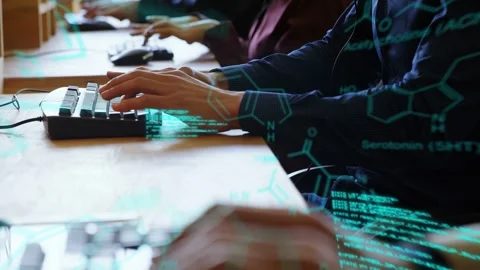 Typist's hands typing at shared desk, activating scrolling teal code and Stock Footage 333287954
