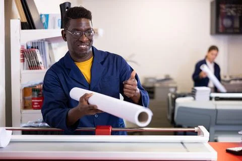Typography technician offering plotter paper roll Fotos de archivo