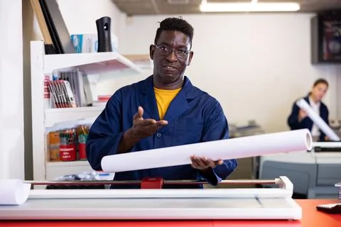 Typography technician offering plotter paper roll Fotos de archivo