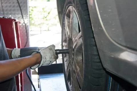 Tyre repairer fixing a wheel using an impact wrench Stock Photos