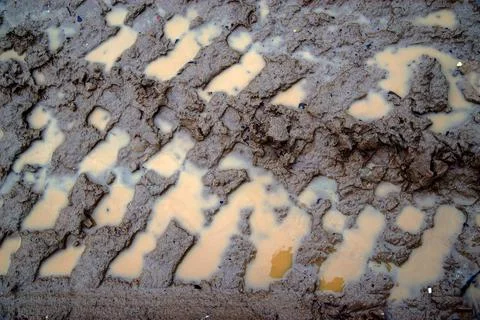 Tyre Tracks In The Mud. mud puddle and tire tracks on meadow road. Stock Photos