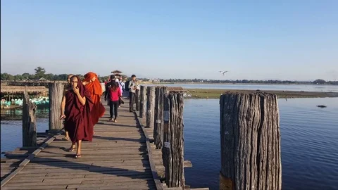 U Bein Bridge, young robed monks and tourists walk, man flies drone, Mandalay Stockbeeldmateriaal 79622779