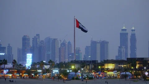UAE flag flapping between the towers of the downtown Dubai skyline and Stock Footage 103272356