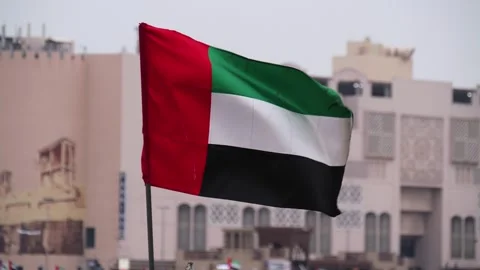 UAE flag waving before Old Dubai buildings in Dubai, United Arab Emirates Stock Footage 329329555