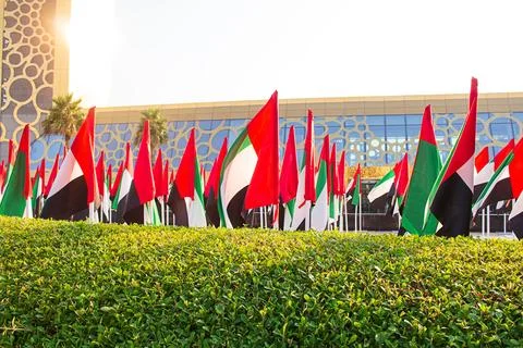 UAE flags waving in the wind in front of a modern glass building Foto stock