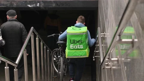 Uber Eats bicycle driver stepping down the underground crossing stairs wearing b Stock Footage 183413824