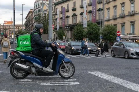 Uber Eats, boy with scooter, delivers food to home, with the typical green ba Stock Photos