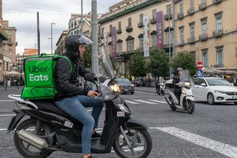 Uber Eats, boy with scooter, delivers food to home, with the typical green ba Stock Photos