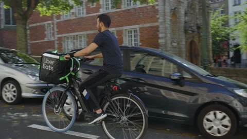 Uber Eats delivery bike rider passing fanfare music parade downtown Stock Footage 209432485