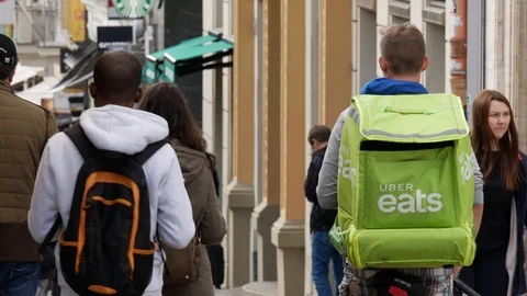 Uber eats delivery guy waiting for an order on a busy street Video stock 108008719