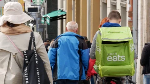 Uber eats delivery guy waiting for an order on a busy street Stock Footage 108008759
