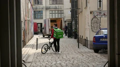 Uber Eats delivery Man with Bicycle walks along City Street - Wroclaw, Poland Stock Footage 152767063