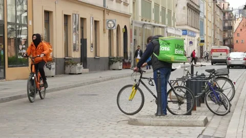 Uber Eats delivery Man sits on a Bicycle in City Street - Wroclaw, Poland Stock Footage 153095473