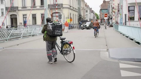 Uber Eats delivery rider with mechanical problem walking next to bike in Stock Footage 196882255