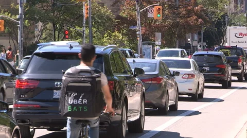 Uber eats driver on bike delivers food in traffic jam Stock Footage 67413624