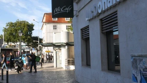 Uber Eats food delivery driver on a vespa picking up food from a McDonald's fast Stock Footage 110876543
