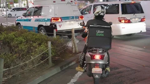 Uber Eats Food Delivery Motorcyclist Waiting At Shibuya Crossing In Tokyo, Stock Footage 142486136