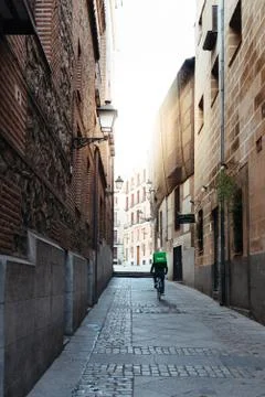 Uber Eats rider cycling through an alley in old Madrid Stock Photos